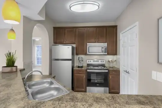 kitchen featuring vaulted ceiling, stainless steel microwave, refrigerator, electric range oven, dark brown cabinets, dark stone countertops, and pendant lighting