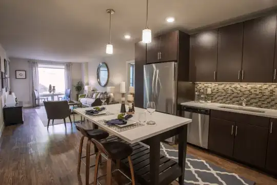 kitchen featuring natural light, stainless steel appliances, dark brown cabinets, light countertops, pendant lighting, and light hardwood flooring
