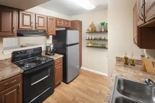 kitchen featuring refrigerator, electric range oven, fume extractor, light granite-like countertops, brown cabinetry, and light parquet floors
