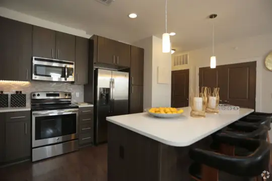 kitchen featuring a breakfast bar area, electric range oven, stainless steel appliances, light countertops, dark parquet floors, pendant lighting, and dark brown cabinets