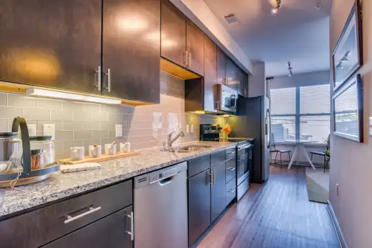 kitchen featuring natural light, refrigerator, stainless steel dishwasher, electric range oven, microwave, stone countertops, pendant lighting, dark brown cabinetry, and light parquet floors