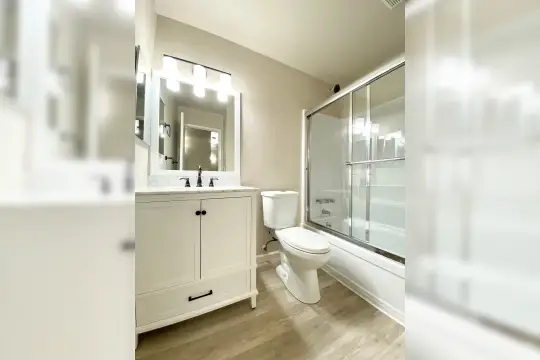 full bathroom with parquet floors, multiple mirrors, bath / shower combination, vanity with extensive cabinet space, and toilet