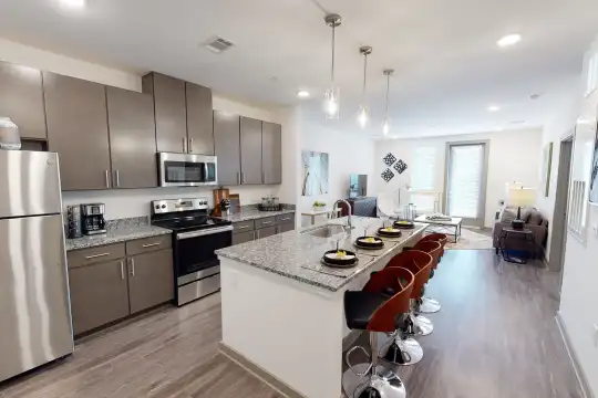 kitchen featuring stainless steel appliances, electric range oven, stone countertops, pendant lighting, light hardwood flooring, and dark brown cabinets