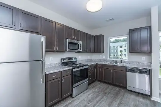 kitchen featuring natural light, electric range oven, stainless steel appliances, dark brown cabinetry, light granite-like countertops, and light parquet floors