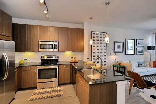 kitchen featuring stainless steel appliances, electric range oven, dark brown cabinets, dark granite-like countertops, pendant lighting, and light hardwood floors