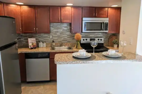 kitchen featuring stainless steel appliances, range oven, dark brown cabinetry, light granite-like countertops, and light tile floors