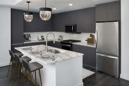 kitchen featuring a kitchen bar, stainless steel appliances, range oven, light granite-like countertops, dark brown cabinetry, pendant lighting, an island with sink, and dark hardwood floors