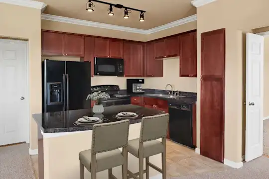 kitchen with carpet, range oven, refrigerator, dishwasher, microwave, dark countertops, light flooring, and dark brown cabinets