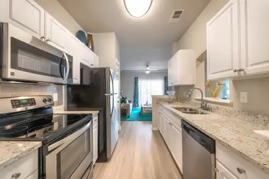 kitchen featuring natural light, electric range oven, stainless steel appliances, light hardwood floors, white cabinetry, and light granite-like countertops