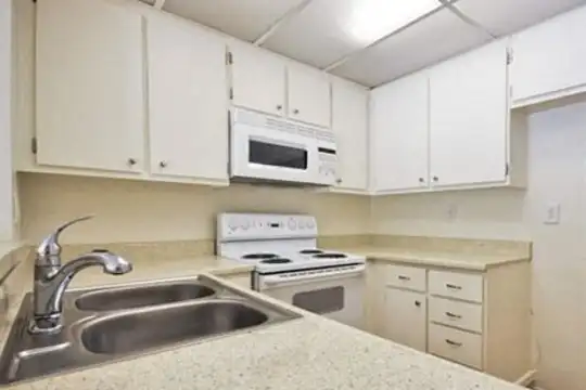 kitchen with electric range oven, microwave, white cabinets, and light granite-like countertops