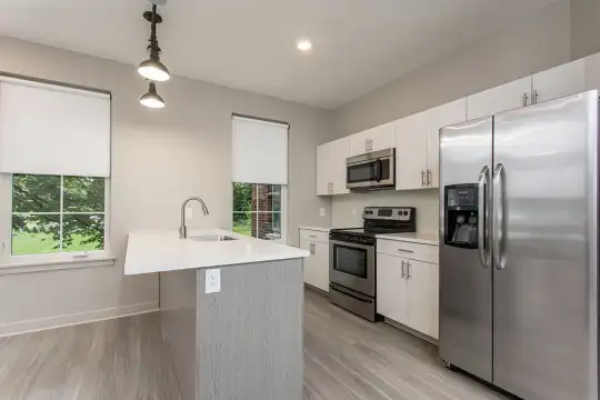 kitchen with a healthy amount of sunlight, electric range oven, stainless steel appliances, white cabinets, light hardwood floors, light countertops, and pendant lighting