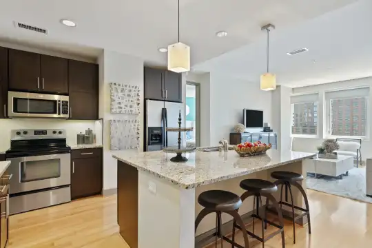kitchen featuring natural light, a breakfast bar area, TV, electric range oven, stainless steel appliances, white cabinetry, light hardwood floors, pendant lighting, and light stone countertops