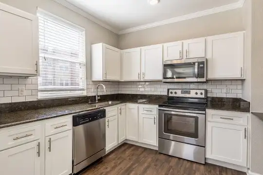 kitchen featuring natural light, stainless steel appliances, electric range oven, white cabinetry, dark parquet floors, and dark granite-like countertops