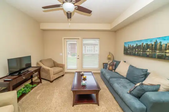 carpeted living room with a ceiling fan and TV