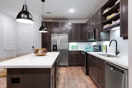 kitchen featuring a center island, electric range oven, stainless steel appliances, pendant lighting, light countertops, dark brown cabinets, and light hardwood flooring