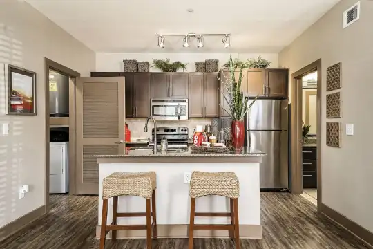 kitchen featuring stainless steel appliances, range oven, dark hardwood flooring, light granite-like countertops, and dark brown cabinets
