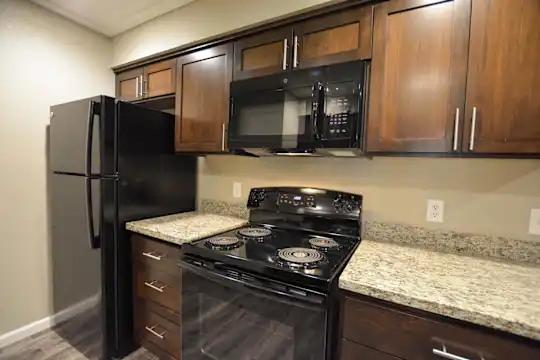 kitchen with refrigerator, electric range oven, microwave, light floors, dark brown cabinetry, and light granite-like countertops