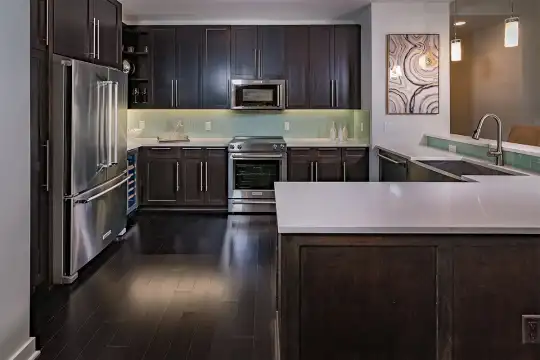 kitchen with stainless steel appliances, range oven, pendant lighting, light countertops, dark brown cabinets, and dark hardwood floors