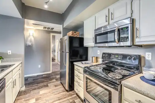 kitchen featuring electric range oven, refrigerator, dishwasher, stainless steel microwave, dark hardwood flooring, white cabinets, and light granite-like countertops