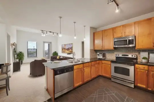 kitchen with stainless steel appliances, electric range oven, brown cabinetry, pendant lighting, dark parquet floors, and dark stone countertops