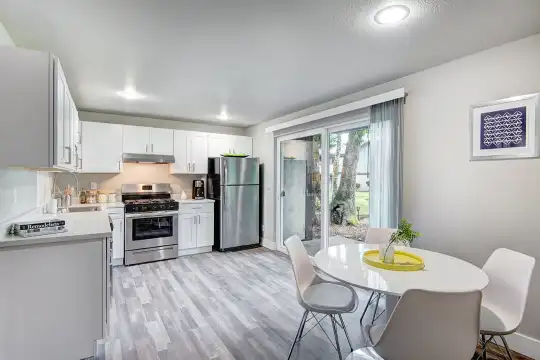 kitchen featuring gas range oven, stainless steel refrigerator, fume extractor, light floors, light countertops, and white cabinets