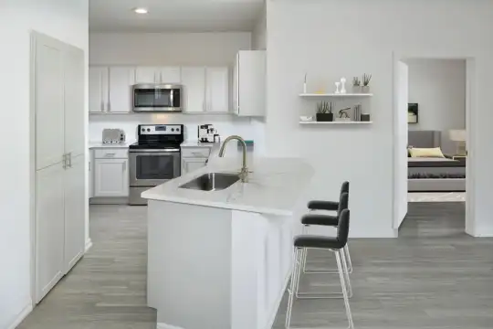 kitchen featuring a breakfast bar, stainless steel microwave, range oven, white cabinets, light granite-like countertops, and light hardwood floors