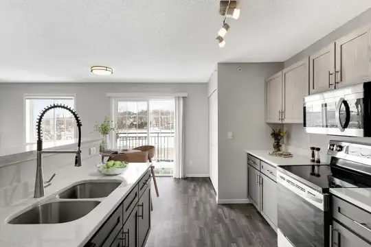 kitchen with plenty of natural light, electric range oven, stainless steel microwave, dark hardwood floors, white cabinetry, and light granite-like countertops