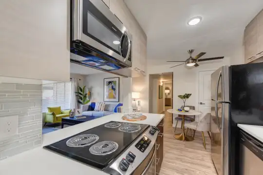 kitchen featuring a ceiling fan, stainless steel appliances, light brown cabinetry, light countertops, pendant lighting, and light hardwood flooring