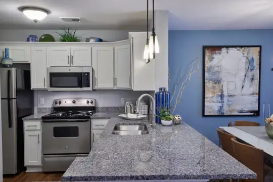 kitchen featuring refrigerator, electric range oven, stainless steel microwave, stone countertops, pendant lighting, white cabinets, and dark flooring