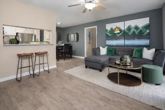 hardwood floored living room featuring a ceiling fan, a kitchen breakfast bar, and refrigerator