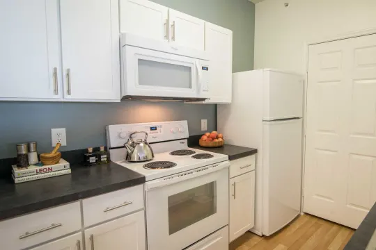 kitchen featuring refrigerator, electric range oven, microwave, white cabinetry, dark countertops, and light parquet floors