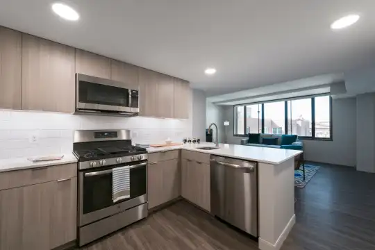 kitchen featuring natural light, gas range oven, stainless steel appliances, dark parquet floors, light countertops, and light brown cabinets