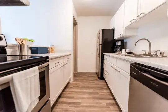 kitchen featuring refrigerator, electric range oven, stainless steel dishwasher, light granite-like countertops, white cabinetry, and light parquet floors
