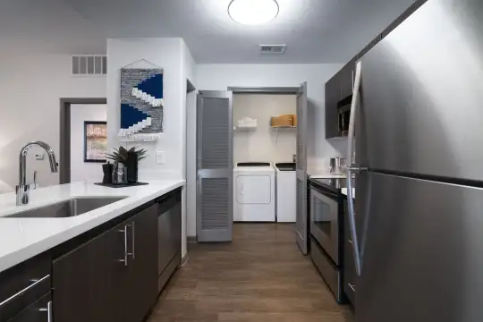 kitchen featuring stainless steel refrigerator, separate washer and dryer, dishwasher, range oven, dark hardwood flooring, dark brown cabinetry, and light countertops