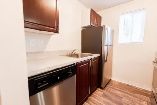 kitchen featuring natural light, refrigerator, stainless steel dishwasher, range oven, dark brown cabinets, light stone countertops, and light hardwood flooring