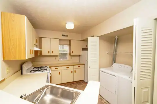 kitchen featuring exhaust hood, refrigerator, gas range oven, independent washer and dryer, white cabinetry, light floors, and light countertops