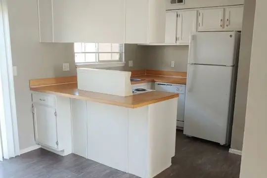kitchen with a kitchen island, natural light, refrigerator, dishwasher, white cabinets, light countertops, and dark hardwood flooring