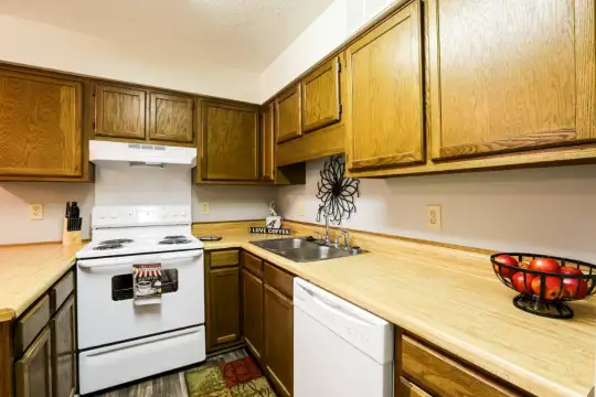 kitchen featuring electric range oven, dishwasher, fume extractor, light countertops, brown cabinets, and dark floors