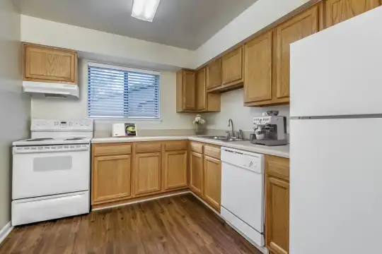 kitchen featuring natural light, refrigerator, electric range oven, dishwasher, fume extractor, dark parquet floors, light countertops, and brown cabinetry
