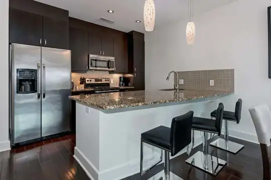 kitchen featuring a breakfast bar, stainless steel appliances, range oven, granite-like countertops, dark brown cabinetry, dark parquet floors, and pendant lighting