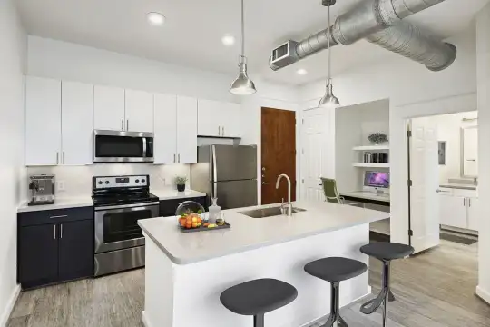 kitchen featuring a breakfast bar area, stainless steel appliances, electric range oven, white cabinetry, light countertops, kitchen island sink, light hardwood flooring, and pendant lighting