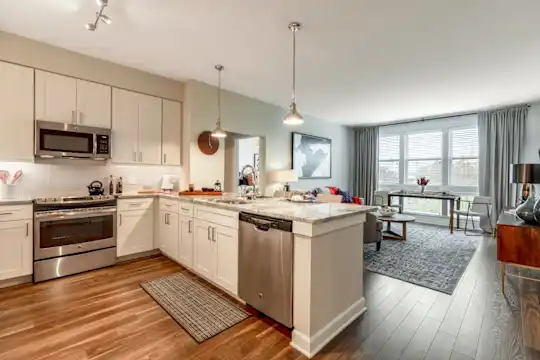 kitchen featuring natural light, stainless steel appliances, range oven, white cabinetry, light granite-like countertops, pendant lighting, and dark hardwood floors