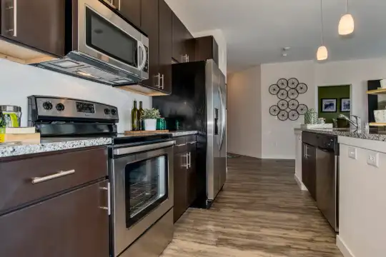 kitchen featuring stainless steel appliances, electric range oven, granite-like countertops, pendant lighting, dark floors, and dark brown cabinets