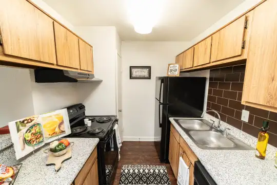 kitchen featuring dishwasher, refrigerator, electric range oven, range hood, dark flooring, light stone countertops, and brown cabinets