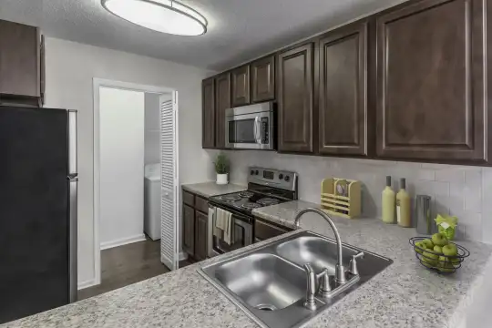 kitchen featuring refrigerator, electric range oven, stainless steel microwave, dark hardwood flooring, light stone countertops, and dark brown cabinets