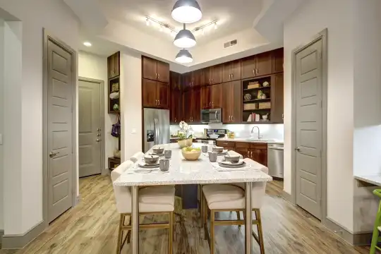 kitchen featuring stainless steel appliances, range oven, dark brown cabinetry, light granite-like countertops, and light hardwood floors
