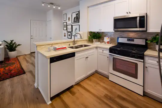 kitchen featuring stainless steel appliances, gas range oven, light countertops, white cabinets, and light hardwood floors