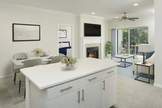 kitchen featuring a fireplace, carpet, natural light, a ceiling fan, a center island, TV, light flooring, light countertops, and white cabinetry