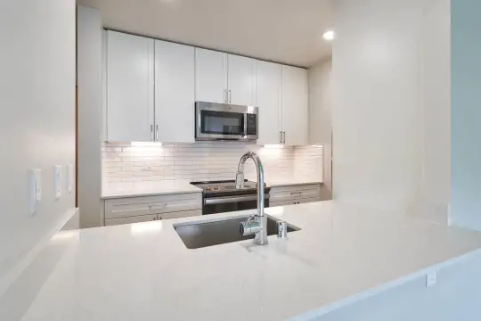 kitchen with range oven, stainless steel microwave, white cabinetry, and light countertops