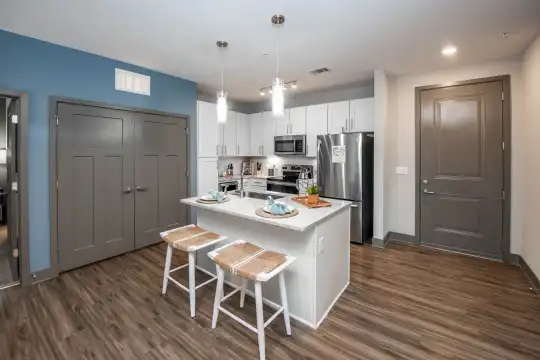 kitchen with a breakfast bar area, stainless steel refrigerator, microwave, range oven, dark parquet floors, pendant lighting, white cabinets, and light granite-like countertops